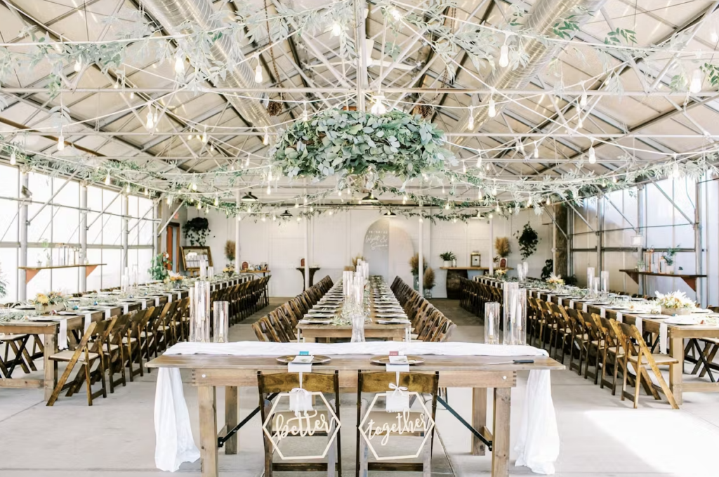 A wide shot of The Greenhouse at Bittersweet with natural light and tables decorated for a wedding reception.